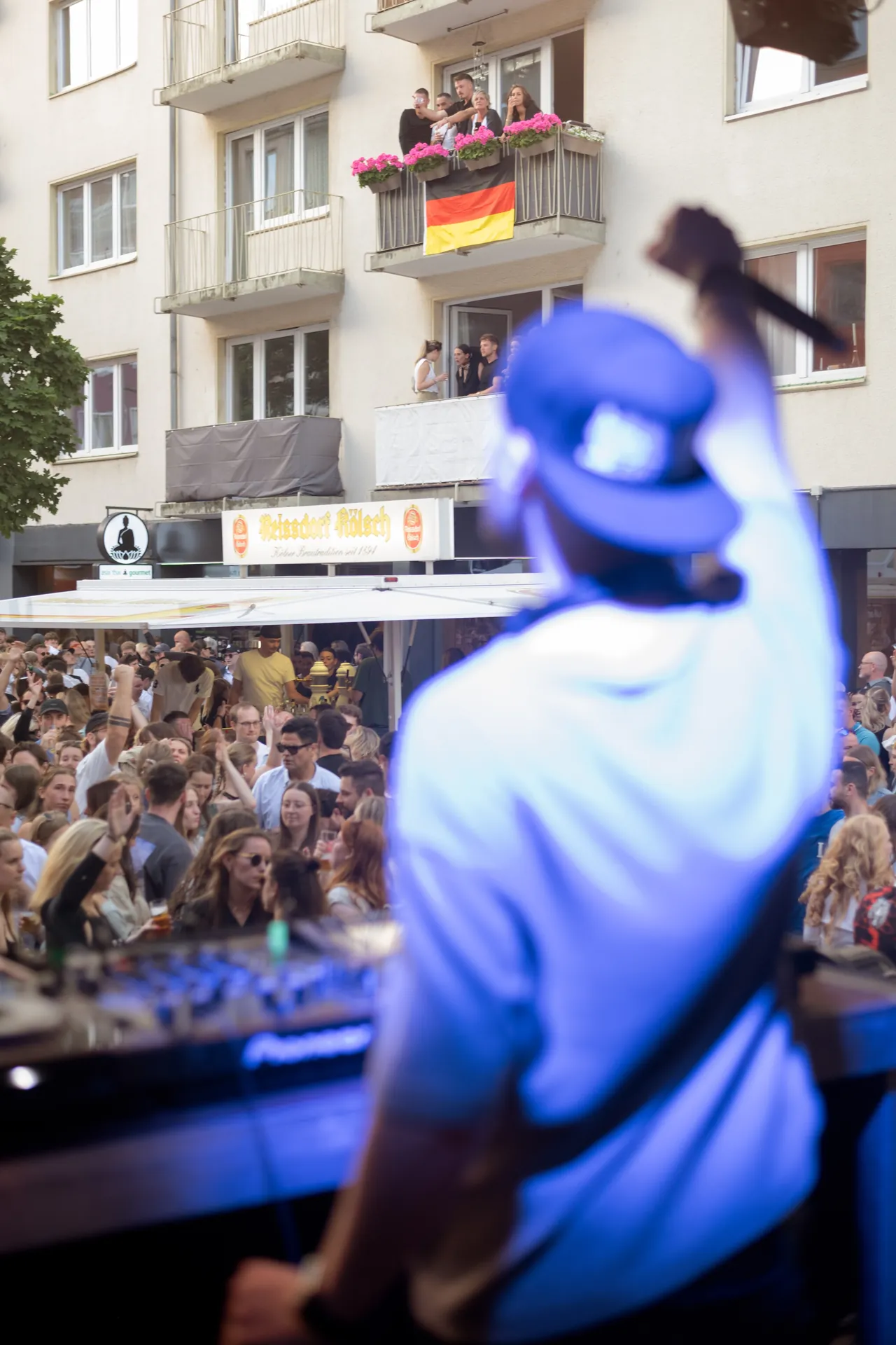 Ein DJ legt vor einer grossen Menge auf, die auf der Bonner Strasse in Koln feiert.