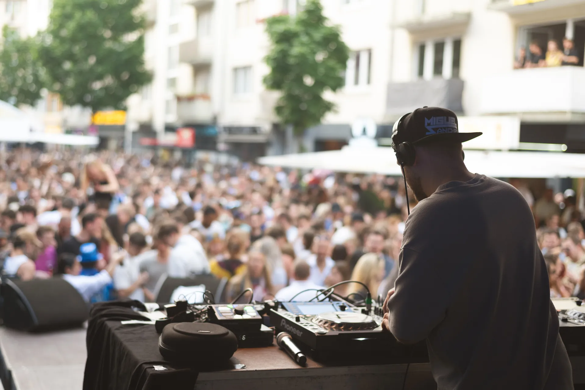 Ein DJ legt vor einer großen Menschenmenge auf, die sich auf dem Platz versammelt hat.