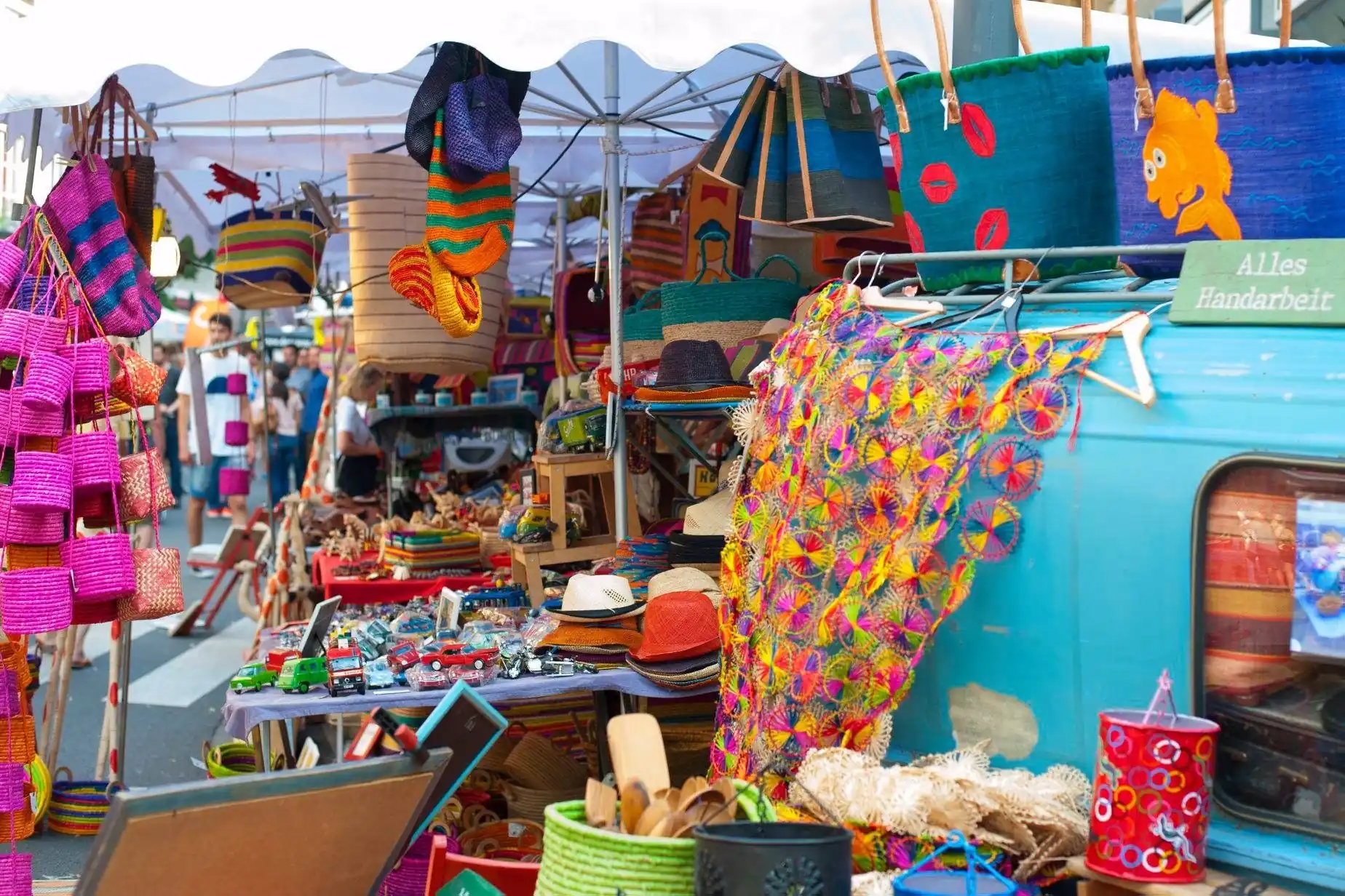 Ein bunter Marktstand prasentiert eine Vielfalt an handgefertigten Waren wie Taschen, Hute und bunte Tucher fur interessierte Kaufer.