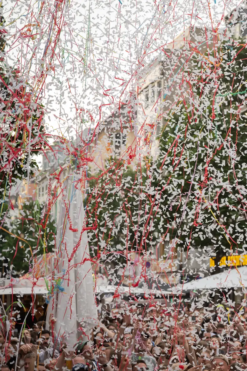 Ein großer Konfettiregen aus weißen Schnipseln und bunten Bändern fällt auf eine feiernde Menschenmenge auf dem Südstadtfest.