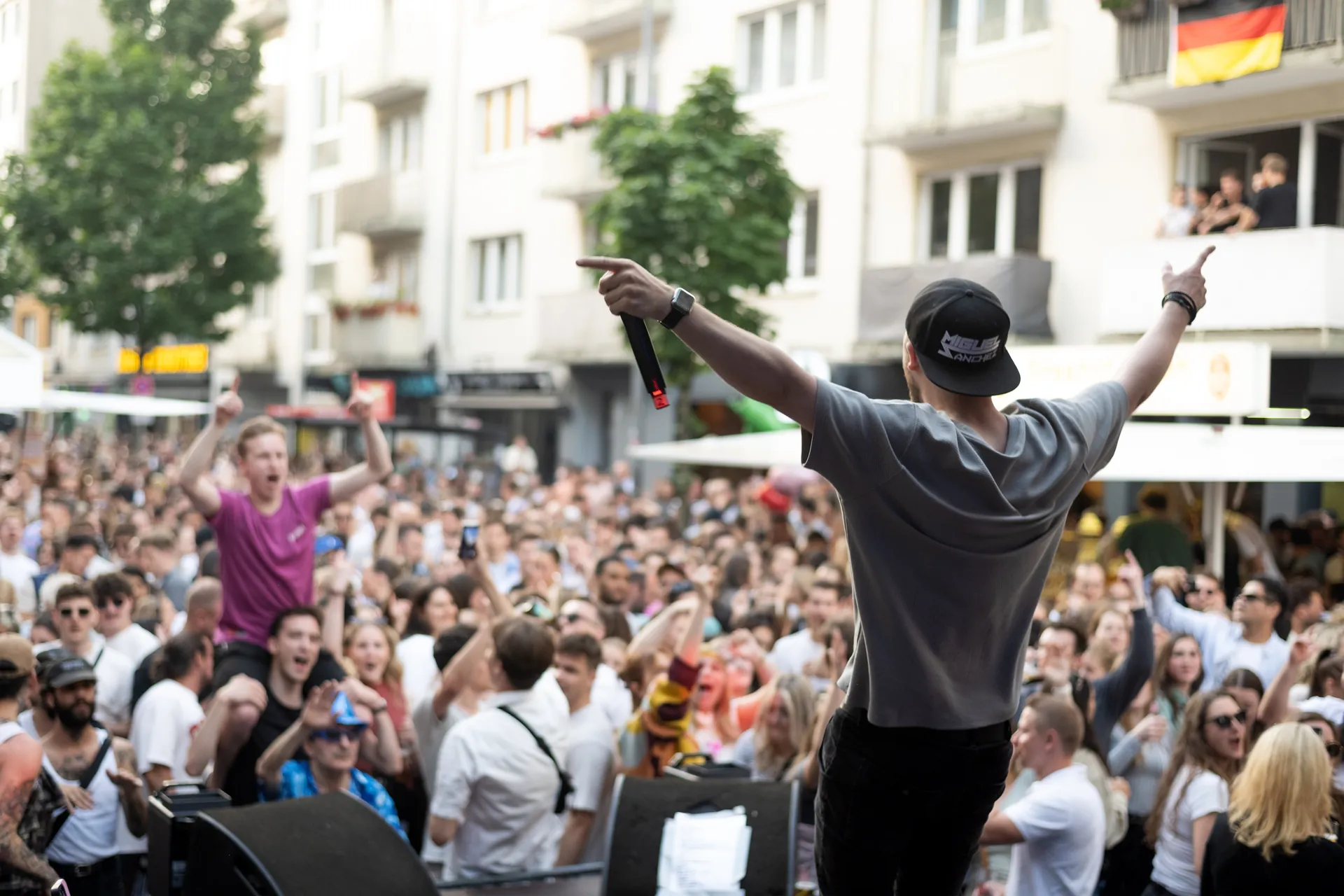 Ein Sänger steht auf der Bühne und performt vor einem großen, begeisterten Publikum an der Bonner Straße.