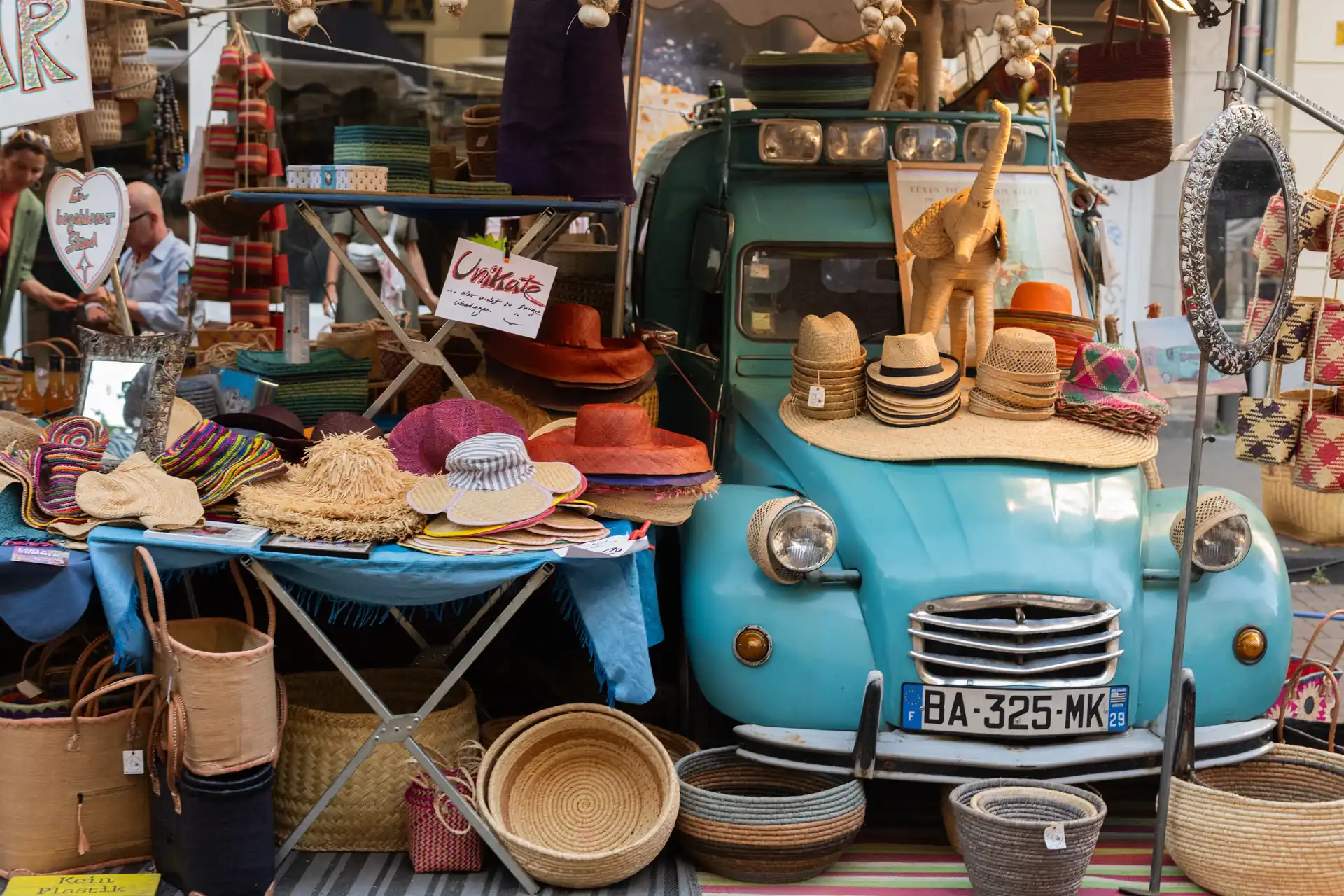 Ein blauer Oldtimer dient als Verkaufsstand fur Hute und geflochtene Korbe auf dem Sudstadtfest.