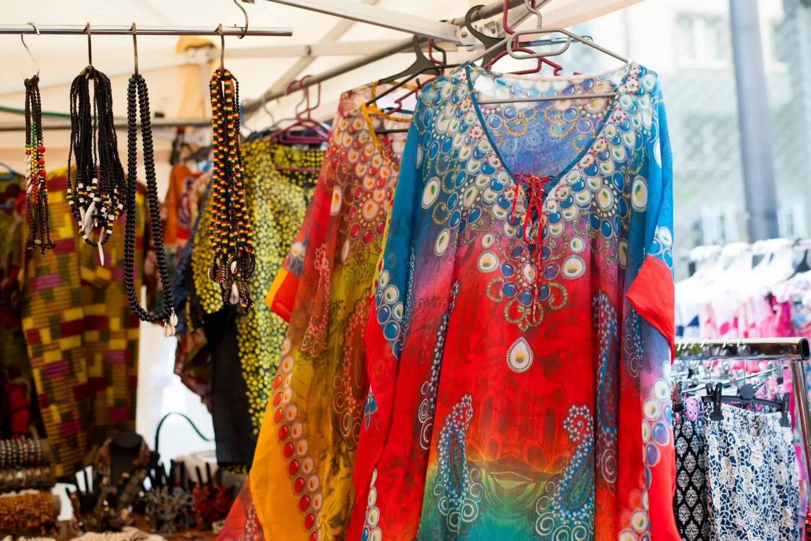 Bunte Kleider und handgemachte Perlenketten an einem Marktstand