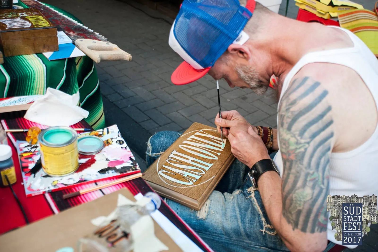 Künstler malt Schriftzug auf ein Holzschild auf dem Südstadtfest