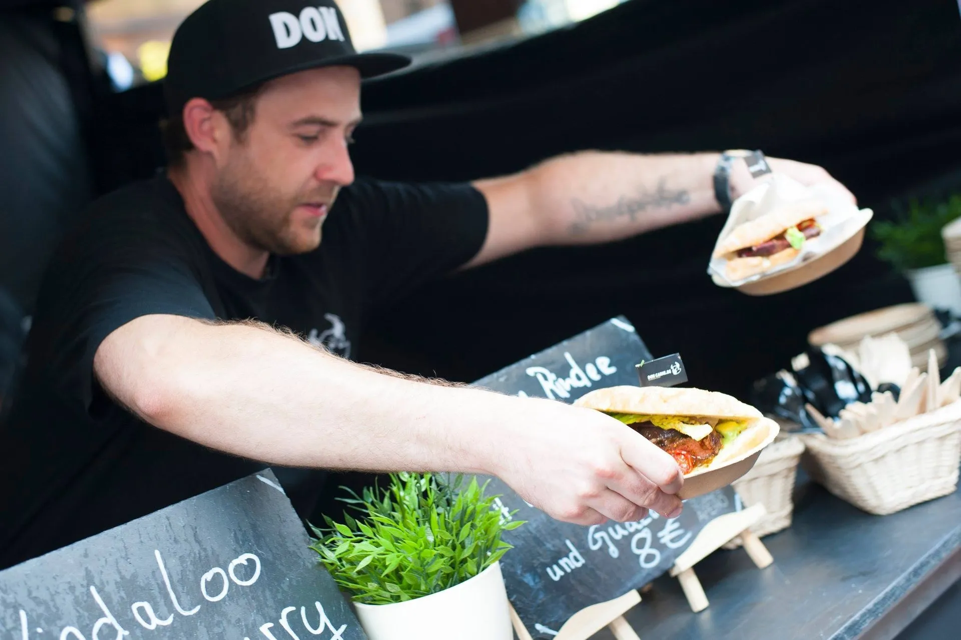Streetfood-Verkäufer reicht sorgfältig ein frisch belegtes Sandwich über die Theke