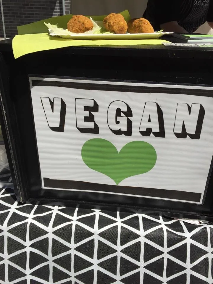 Drei vegane Bällchen auf einem Teller mit Salat vor einem Schild mit der Aufschrift VEGAN